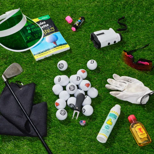 Assorted golf-related items scattered on AstroTurf. Includes golf clubs, balls, and drinks.